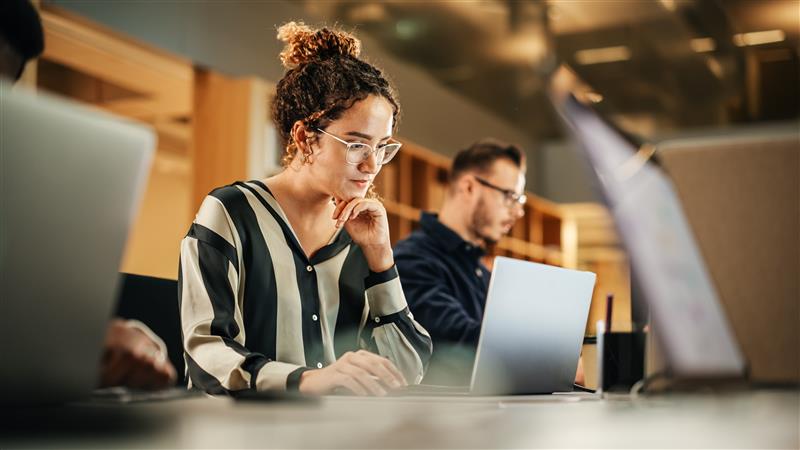 Woman sat at a desk looking at a laptop