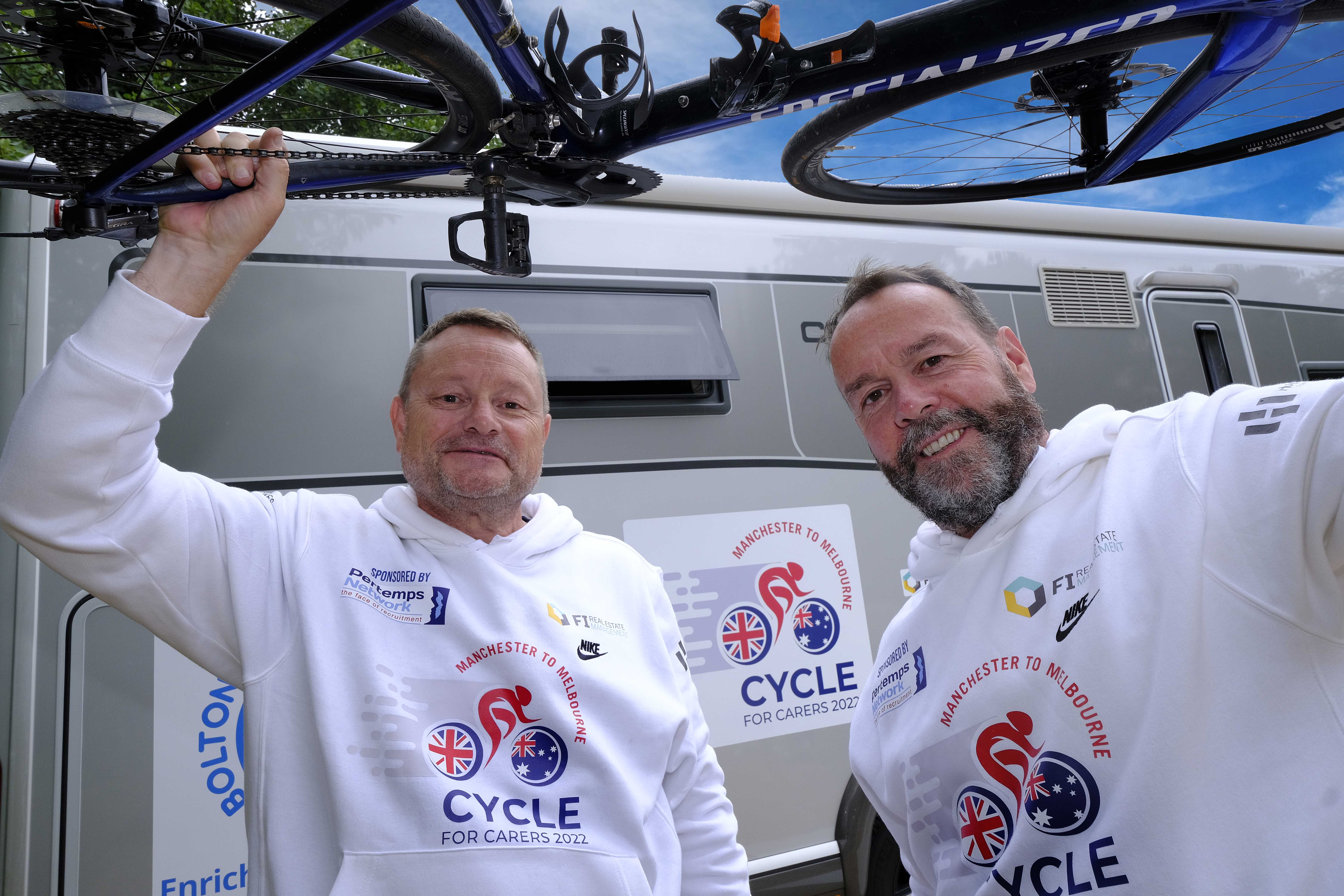 Cyclists holding a bike above their heads