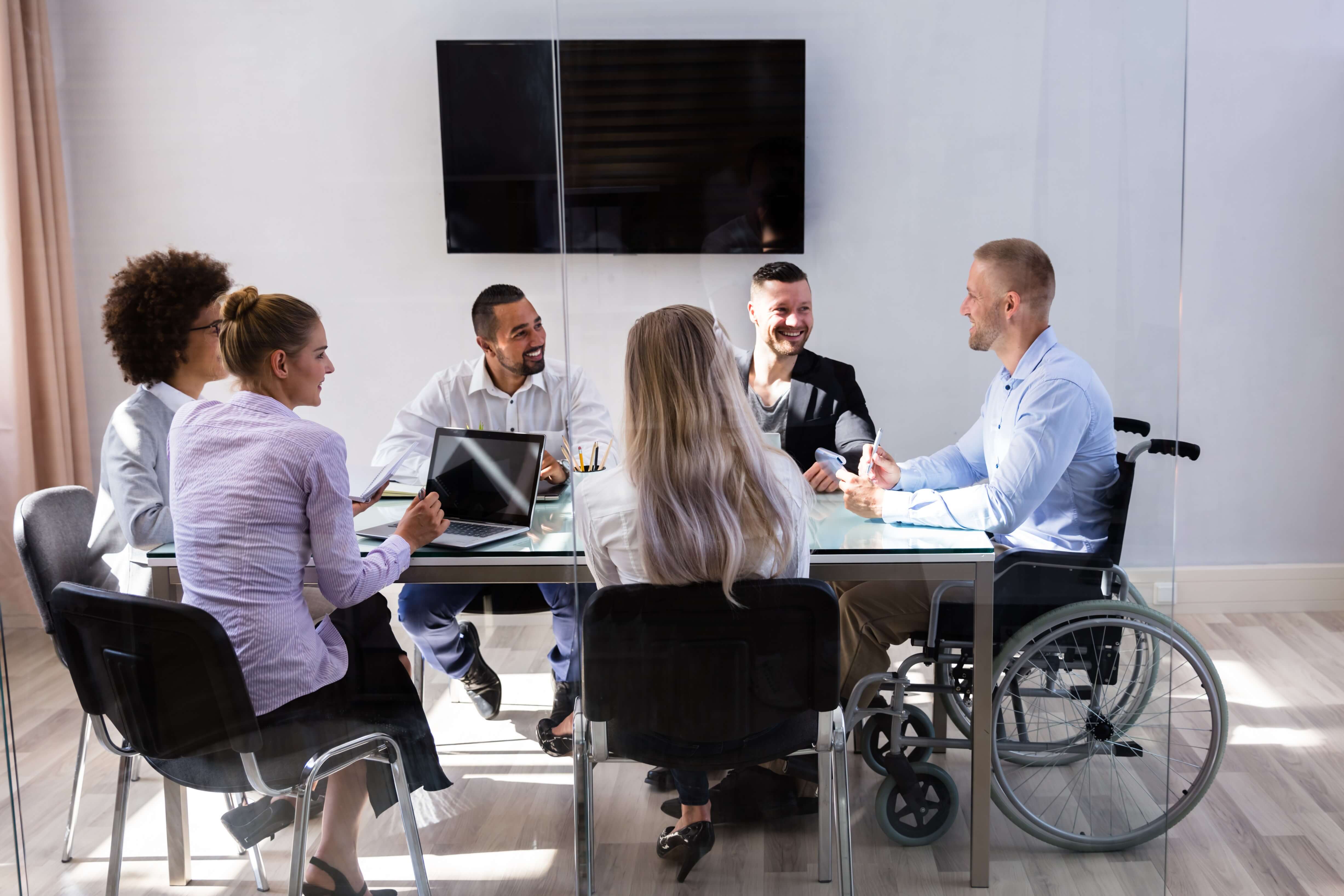 Workers in wheelchairs sat around a meeting table in an office