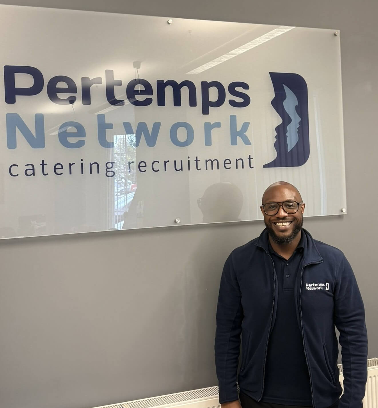 worker stood beside company sign 